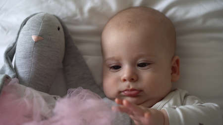 Close-up Happy playful kid 6 month old. Newborn boy looking at camera after bath shower on white soft bed. baby child waking time before bedtime with Toy. Childhood, motherhood, family, infant conceptの写真素材