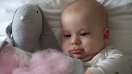 Close-up Happy playful kid 6 month old. Newborn boy looking at camera after bath shower on white soft bed. baby child waking time before bedtime with Toy. Childhood, motherhood, family, infant conceptの写真素材