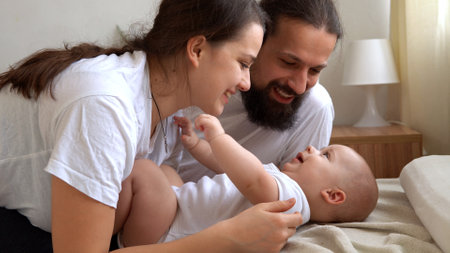 Woman And Man Holding Newborn. Mom, Dad And Baby On Bed. Close-up. Portrait of Young Smiling Family With Newborn On Hands. Happy Marriage Couple On Background. Childhood, Parenthood, Infants Conceptの写真素材