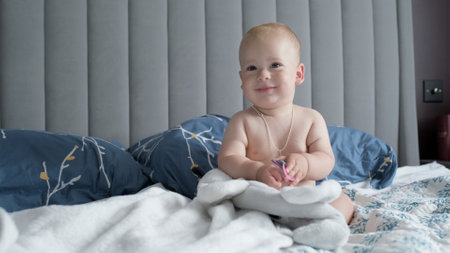 Close-up Happy playful sleepy kid 10 month old. Newborn boy looking at camera after bath shower on white soft bed. baby child yawns time before bedtime. Childhood, motherhood, family, infant conceptの写真素材