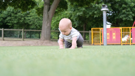 Happy family having picnic. Little Baby is crawling on green grass. Summer in park. Siblings children Playing in green park. Family fun and joy in Playgroung. Active son crawls barefoot in the fieldの写真素材