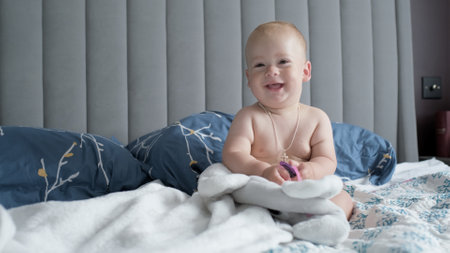 Close-up Happy playful sleepy kid 10 month old. Newborn boy looking at camera after bath shower on white soft bed. baby child yawns time before bedtime. Childhood, motherhood, family, infant conceptの写真素材