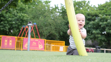 Happy family having picnic. Little Baby is crawling on green grass. Summer in park. Siblings children Playing in green park. Family fun and joy in Playgroung. Active son crawls barefoot in the fieldの写真素材