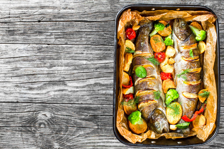 whole trout fishes grilled with potatoes, broccoli, lemon, tomatoes, top viewの写真素材