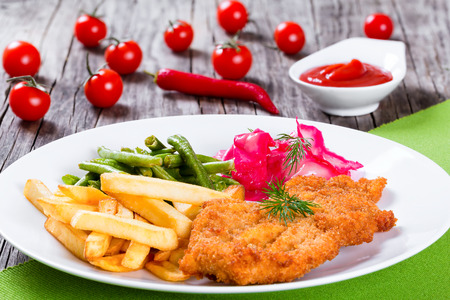 Bread Crumb Coated fried pork chop with french fries, fried green bean and salad with dill and cabbage marinated in red wine vinegar and beet juice, studio lights, close-upの写真素材