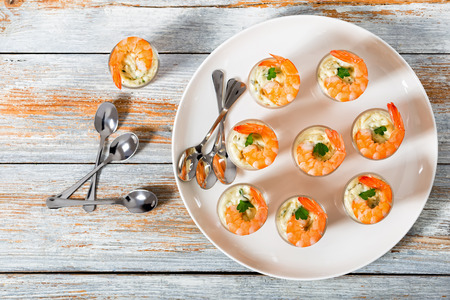 Shot-Glass Shrimp with tartar sauce - easy cocktail recipe for festive party, on white platter with spoons on old white wooden table, view from aboveの写真素材