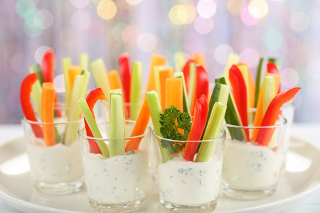 Verrines appetizer with carrot, cucumber, celery and red bell pepper sticks in glasses on platter at bokeh background, view from above, close-upの写真素材