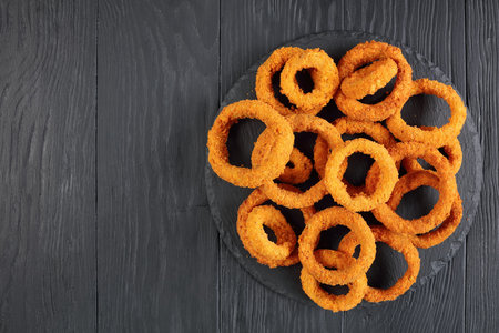delicious golden battered, breaded and deep fried crispy onion rings served on round black stone...