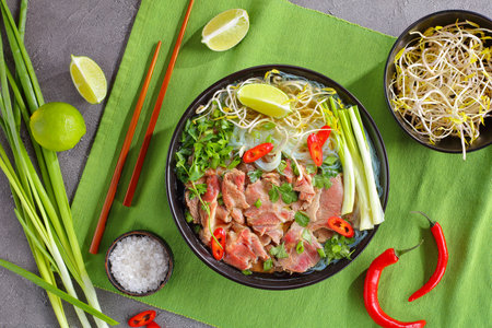 Vietnamese soup Pho Bo with rice noodle, raw sirloin beef slices, bean sprouts, lime, spring onion...