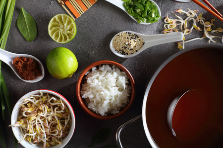 ingredients for miso soup on concrete background - dashi with miso paste in pan,  miso paste, sesame seeds, steamed rice, spinach, bean sprouts, green onion, view from aboveの写真素材