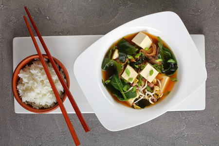 close-up of miso soup served in a white bowl with chopsticks and steamed rice, view from aboveの写真素材