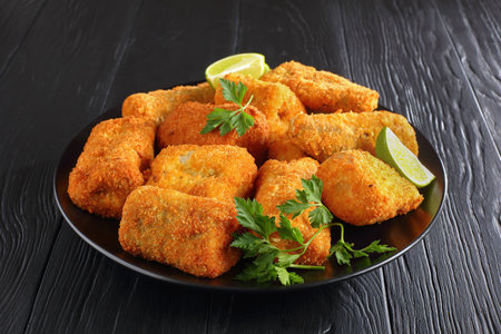 baked in oven delicious pieces of white fish breaded with coconut and bread crumbs  on black plate...