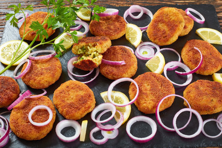 delicious crispy rice patties with crumbled paneer cheese and finely chopped greens on a black slate...