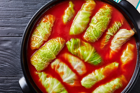 overhead view of raw cabbage leaves rolls stuffed with minced beef, boiled rice prepared to cook with tomato sauce in dutch oven, view from above, flatlay,, close-up, copy spaceの写真素材