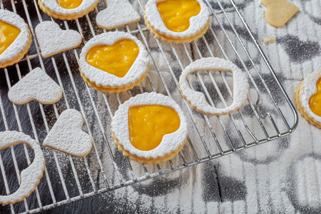 Heart shaped linzer cookies with organic mango jam sprinkled with powdered sugar on a wire rack on a...