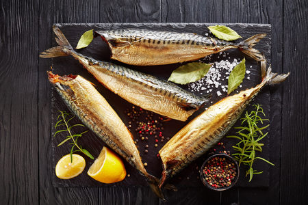 Hot smoked mackerel on a black slate tray with salt, peppercorn, rosemary and lemon, view from above, flatlay, cclose-upの写真素材