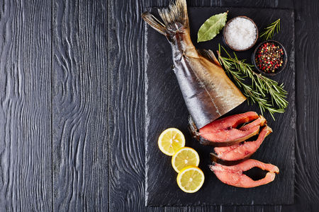 wild salmon cut in steaks with fresh rosemary salt and peppercorn on a black stone tray, view from above, close-up, flat lay, copy spaceの写真素材