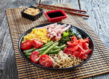 Hiyashi chuka, cold ramen - chilled egg noodles,  topped with vegetables, seaweeds, pickled red ginger - beni shoga, strips of egg crepes and ham, horizontal view from aboveの写真素材