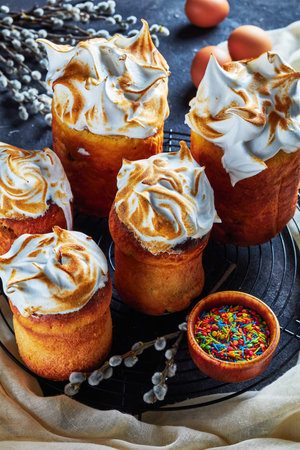 delicious sweet easter bread, panettone topped with whipped egg whites on a wire rack on a concrete...