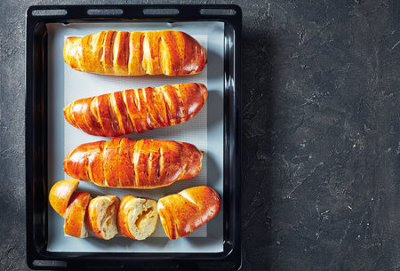 freshly baked yeast dough rolls with Apple filling on a baking pan on a kitchen concrete table,...
