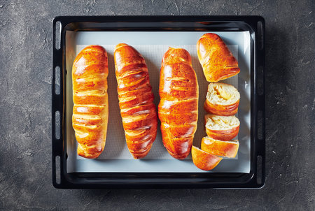 overhead view of freshly baked yeast dough rolls with Apple filling on a baking pan on a kitchen...