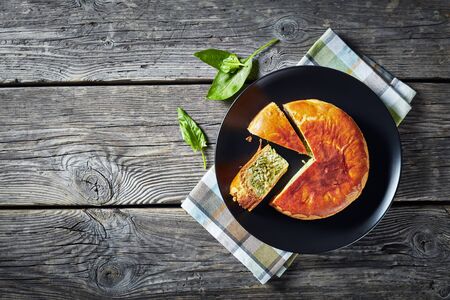 Green Bean spinach and blue cheese pie on a black plate on a rustic wooden table, horizontal view from above, flat layの写真素材