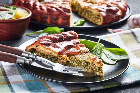close-up of a slice of Spinach Ricotta pie served on a black plate with sliced pie at the background, horizontal view from aboveの写真素材