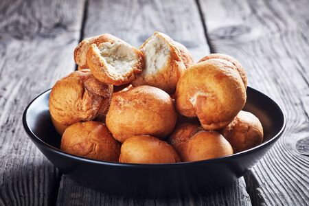 Caribbean fried dumplings in a black bowl on an old wooden rustic table, close-upの写真素材