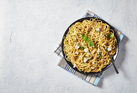 overhead view of Spaghetti with genovese basil pesto and blue cheese on a black plate on a white concrete table, view from above, flatlay, close-upの写真素材