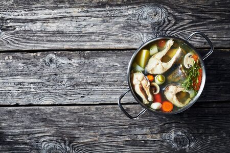 Delicious spicy Trout fish soup with vegetables and mushrooms in a pot on a wooden rustic table, horizontal view from aboveの写真素材