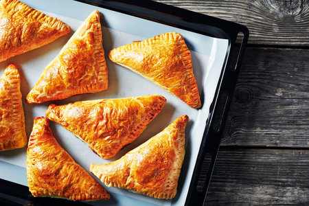 freshly baked puff pastry apple turnover on a sheet pan on an old wooden table, view from above, flatlay, close-upの写真素材
