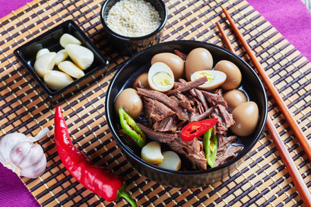 close-up of Jangjorim, beef braised in soy sauce with quail eggs, garlic cloves and chili pepper...