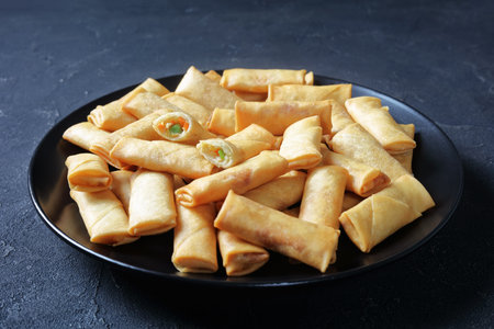 close-up of deep fried crispy bite-sized chinese spring rolls with cabbage, carrots and green peas...