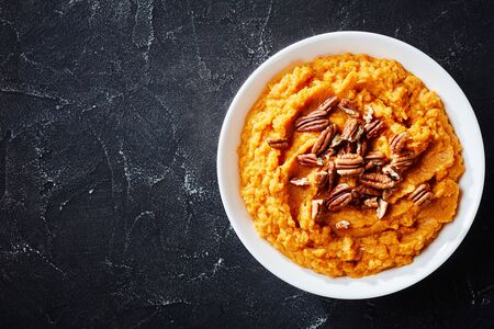close-up of delicious sweet potato mash topped with pecan nuts in a bowl, horizontal view from above, flatlay, free spaceの写真素材