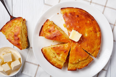 Homemade sliced Buttermilk Cornbread topped with melted butter served on a plate, flatlay, close-up