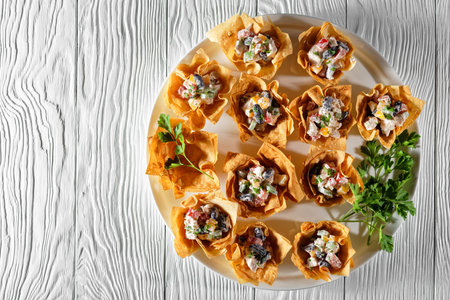 Chicken red bean pepper salad wonton cups served on a white dish on a wooden table, flat lay, free...