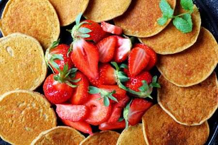 oatmeal gluten free pancakes with strawberries on a black plate, healthy food, horizontal view from above, close-up, flat layの写真素材