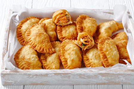 delicious deep-fried RedHot Buffalo Chicken Empanadas in a rustic wooden serving tray, horizontal...