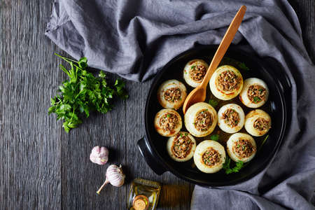 Soft, caramelized, oven-baked onions stuffed with minced lamb and rice in a black ceramic baking dish on a dark wooden table, horizontal view from above, flat lay, free spaceの写真素材