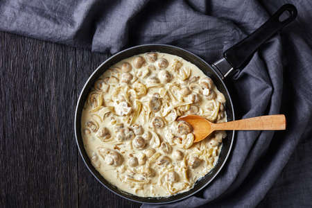 Creamy Garlic Mushrooms, champignons sauteed in sour cream sauce in a skille on a dark wooden table, flat lay, horizontal view from above, free space, close-upの写真素材