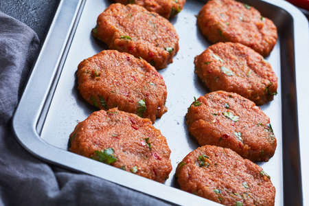 raw thai fish cakes prepared on a baking sheet on a concrete table, view from above, close-upの写真素材
