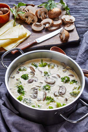 Mushroom Cheese Broccoli Soup in a pot with ingredients at the background, vertical view from above, close-upの写真素材