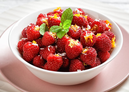 Stuffed raspberries with shredded coconut, honey, and orange zest served on white bowl with fresh...