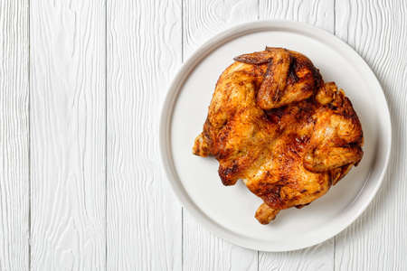 roast chicken served on a white platter on a wooden table, horizontal view from above, close-upflat lay, free spaceの写真素材