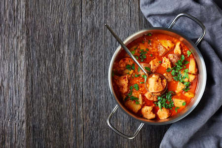 chicken arrabbiata stew with lentil and potato in a pot on a wooden table, horizontal view from above, flat layの写真素材