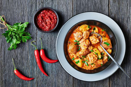 chicken arrabbiata stew with lentil and potato in abowl on a wooden table, horizontal view from above, flat layの写真素材