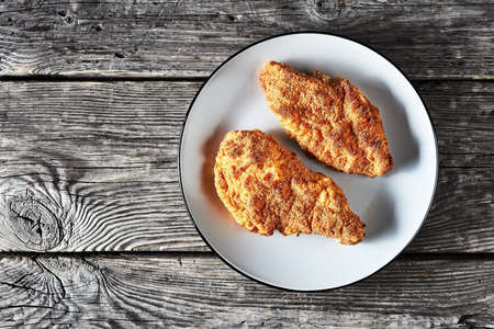 fried breaded chicken breasts on a gray plate on a rustic wooden table, flat lay, free spaceの写真素材