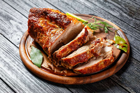 Sunday roasted pork tenderloin, juicy and succulent oven-baked piece of meat rubbed with mustard and spices: rosemary, bay leaf, lime juice, and pepper on a wooden background, close-up, top viewの写真素材