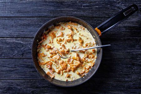 creamy chanterelle sauce in a pan on a wooden kitchen table, french cuisine, horizontal view from above, flat lay, free spaceの写真素材