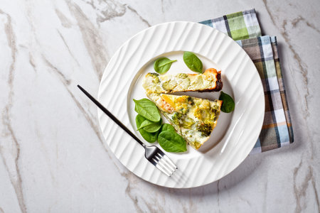 Crustless Broccoli Quiche gluten free with brie and cheddar cheese on a white plate, horizontal view...